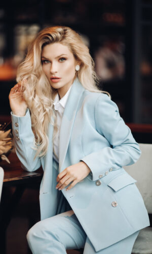Portrait of fashion blonde business woman posing sitting on chair looking at camera